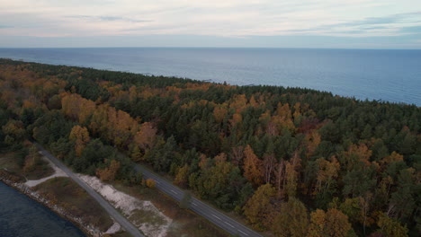 Car-driving-on-a-coastal-road-by-a-forest-with-autumn-colors-at-dusk---Hel-Peninsula