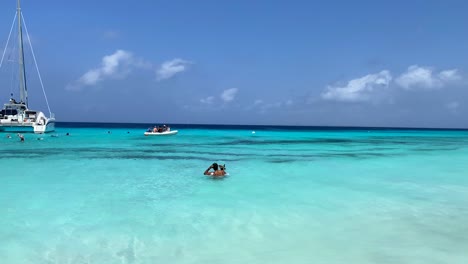 Tropical-white-sand-beach-and-crystal-clear-transparent-turquoise-water-in-Klein-Curaçao,-white-charter-boat,-dream-vacation-destination-in-Little-Curaçao-the-Dutch-Caribbean-island,-4K-shot