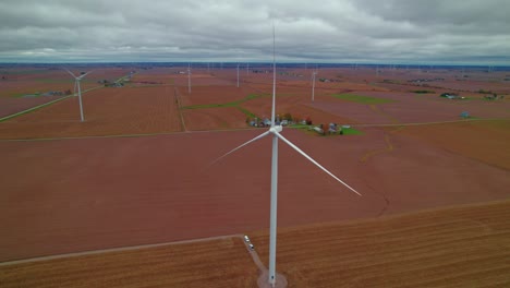 Wind-turbines-tower-over-vast-farmland-under-a-cloudy-sky-in-New-Sharon,-Iowa