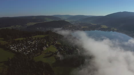 Forward-moving-shot-through-clouds-over-a-mountain-lake