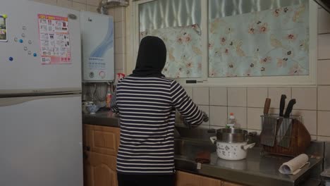 Muslimische-Asiatische-Indonesische-Frau-Im-Hijab,-Die-In-Der-Küche-Geschirr-Spült