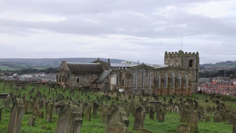 Slow-panning-shot-of-a-cemetery-and-the-historic-town-of-Whitby,-Yorkshire