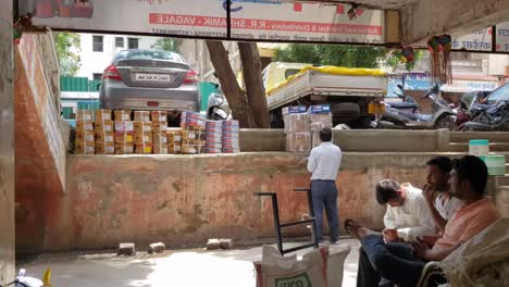 Un-Comerciante-Cuenta-Cajas-De-Cartón-Para-Paquetes-Y-Otros-Clientes-Esperan-En-Una-Silla