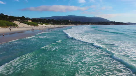 Drone-shot-passing-people-on-the-Carmel-Sunset-Beach,-in-sunny-Monterey,-USA