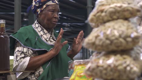 Unbekannte-Traditionelle-ältere-Schwarzafrikanische-Frau,-Die-Auf-Einem-Straßenmarkt-Echte-Lebensmittel-In-Plastiktüten-Verkauft