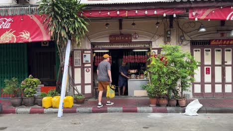 Sicht-Eines-Ladenbesitzers,-Der-Getrocknete-Lebensmittel-Und-Chinesische-Würste-Zubereitet,-Und-Eines-Touristen,-Der-In-Yaowarat-Chinatown,-Bangkok,-Thailand-Vorbeikommt-Und-Es-Auscheckt