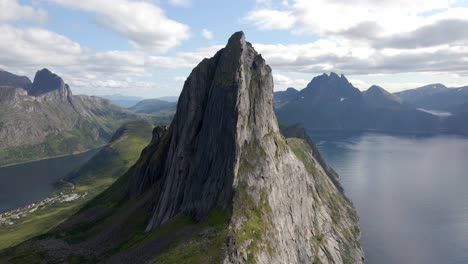 Aerial-tilt-up-shot-of-Senja-Mountains-surrounded-by-Fjord-Sea-in-Norway-during-sunny-day---Cinematic-film-footage