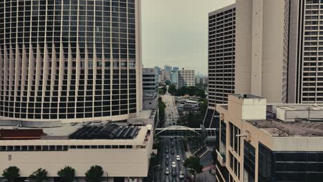 Toma-Aérea-Inclinada-Hacia-Arriba-Del-Hotel-Hilton-Y-Marriot-Marquis-En-El-Centro-De-Atlanta-Con-Tráfico-En-La-Carretera-Principal-En-Un-Día-Nublado,-EE.UU.