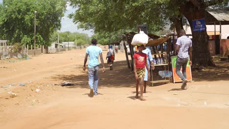 Gruppe-Unbekannter-Menschen,-Die-Ihrem-Täglichen-Leben-Auf-Den-Unbefestigten-Straßen-Ihres-Mittellosen-Ländlichen-Dorfes-In-Afrika-Nachgehen