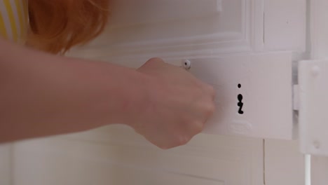 Redhead-woman-trying-to-open-door-with-old-rusty-knob,-close-up