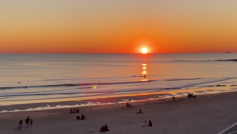 People-enjoying-the-sunset-on-the-beach-in-cascais,-Portugal