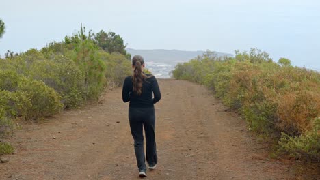 Attractive-jogger-female-in-mountains-of-Tenerife,-back-view