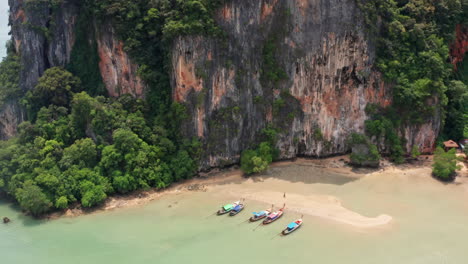 Vista-Aérea-De-Montañas-De-Piedra-Caliza-Y-Botes-De-Cola-Larga-En-La-Playa-Railay,-Krabi,-Tailandia