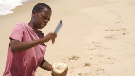 Unbekannter-Junger-Afrikanischer-Stricher-öffnet-Eine-Kokosnuss,-Um-Sie-An-Touristen-Am-Praia-De-Tofo-Zu-Verkaufen