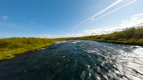 Toma-Aérea-FPV-A-Lo-Largo-De-Un-Río-Que-Fluye-Rápidamente-Con-Una-Pequeña-Cascada-En-Islandia