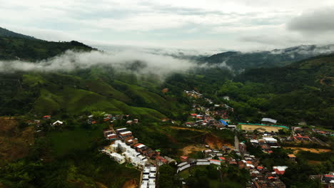 Drone-shot-rising-over-town-and-river-in-the-mountains-of-San-Rafael,-cloudy-Colombia