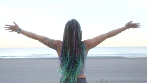 woman-with-braids-breathes-and-spreads-her-arms-on-the-beach