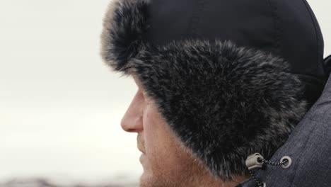 Close-up-of-man-looking-into-far-during-windy-and-bright-day-in-Iceland