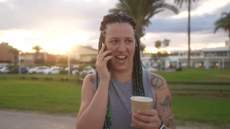 Mujer-Con-Trenzas-Y-Sonrisa-Hablando-Por-Teléfono-Inteligente-Con-Café-En-La-Mano.