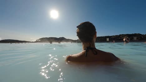 tracking-shot-of-a-beautiful-woman-enjoying-herself-in-the-blue-lagoon-spa-in-Iceland