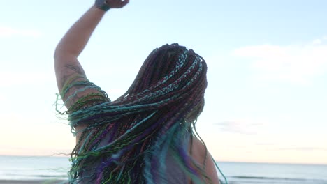 Mujer-Con-Trenzas-Coloridas-Bailando-Con-Libertad-En-La-Playa.