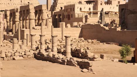 Schwenkaufnahme-Der-Ruinen-Des-Antiken-Luxor-Tempels-Mit-Einer-Moschee-Und-Einem-Minarett-Mit-Säulen-Im-Vordergrund