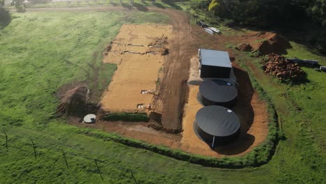 Aerial-top-down-shot-showing-construction-site-for-farm-house-building-in-rural-area-at-farmland-with-silos-at-sunny-day---Australian-scenic-landscape--orbit-shot