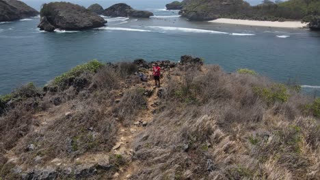 Vista-Aérea-De-Turistas-Saludando-Al-Dron-Y-Mostrando-La-Hermosa-Playa-De-Kasap-Ubicada-En-Pacitan,-Indonesia