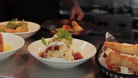 Close-up-shot-of-delicious-Chinese-bao-buns-garnished-with-herbs-and-sauce-while-lime-is-added-by-the-chef-for-a-delicious-meal-with-other-dishes-on-the-side