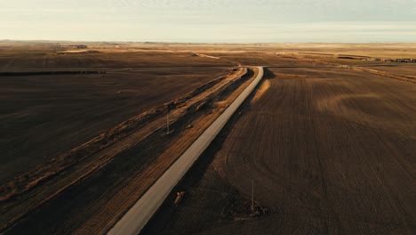 Long-road-through-rural-fields-in-Mossbank,-Saskatchewan,-Canada