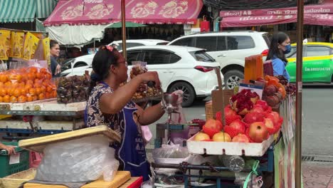 Blick-Auf-Einen-Straßenfruchtsaftverkäufer,-Der-Frischen-Granatapfelsaft-Mit-Einem-Saftmixer-Auf-Der-Straße-In-Yaowarat-Chinatown,-Bangkok,-Thailand-Herstellt