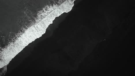 Filmische-Luftaufnahme-Von-Oben-Nach-Unten-Zum-Schwarzen-Sandstrand,-Wellen,-Die-Auf-Vulkanischem-Sand-Island-Krachen,-Zeitlupenfilm