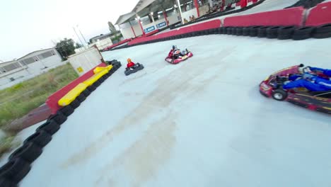 Fpv-racing-drone-flying-above-Go-Kart-pilots-during-race-on-indoor-and-outdoor-racetrack