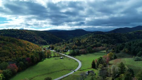 Drone-Hyper-Lapse-over-the-countryside-mountain-valley-with-a-home-below-as-dark-clouds-roll-by-over-autumn-trees