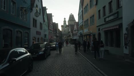 Tourists-explore-cobblestone-path-and-timber-homes-along-idyllic-street-at-dusk