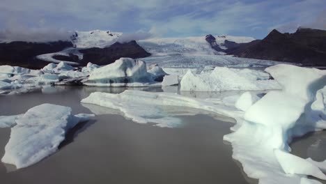 Vuelo-Aéreo-Sobre-Dramáticos-Icebergs-Flotando-En-El-Agua,-Lago-Jokulsarlon,-Clima-Natural-Vista-Del-Paisaje-Nevado,-Islandia