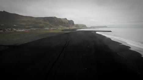 Aerial-black-sand-beach,-ocean-scenery,-moody-dark-cloudy-scenery,-Vik,-Iceland