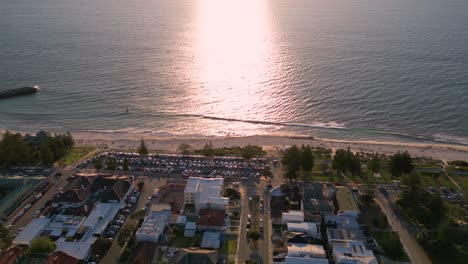 Drone-shot-revealing-cinematic-sunset-view-at-Cottesloe-town-beach-on-the-Indian-Ocean,-Perth,-Western-Australia