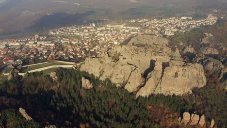 Rising-drone-shot-of-Belogradchik-Fortrees-in-front-of-city-during-sunset-time-in-Bulgaria
