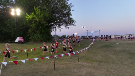 Runners-competing-in-a-high-school-cross-country-event-at-dusk,-with-spectators-lining-the-course