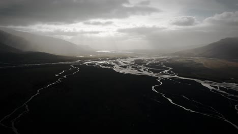 Epic-aerial-thor-valley,-glacial-river-flowing-through-black-volcanic-floodplain,-thorsmörk-dramatic-moody-landscape-Iceland