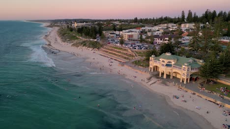 Aerial-view-of-tourist-swimming-and-surfing-at-the-pristine-Cottesloe-beach-on-the-Indian-Ocean-in-the-evening,-Perth,-Western-Australia