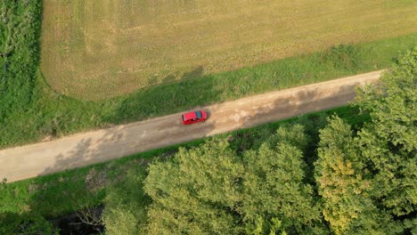 Coche-Rojo-Conduciendo-Por-Una-Carretera-Rural-Cerca-De-Campos-En-Inglaterra