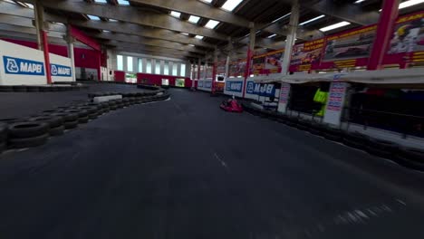 Go-Kart-race-on-indoor-and-outdoor-track-seen-from-racing-Fpv-Drone-point-of-view-flying-at-low-altitude
