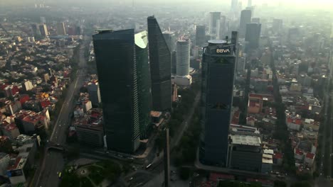 Aerial-orbit-establishing-over-Paseo-de-la-Reforma-in-the-CDMX-with-high-concentration-of-air-pollution,-Estela-de-Luz-Monument