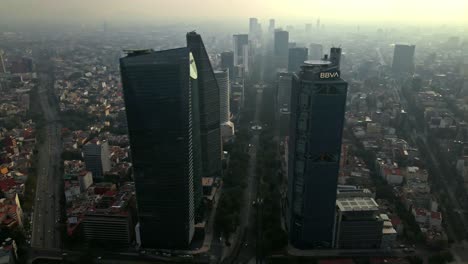 Aerial-view-establishing-over-Paseo-de-la-Reforma-with-the-buildings-covered-and-hidden-by-smog,-pollution-and-poor-air-quality