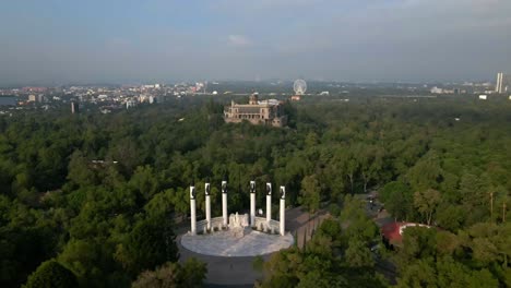 Boom-up-establishing-on-the-Altar-a-la-Patria-with-Chapultepec-Castle-in-the-background,-surrounded-by-a-natural-environment-on-a-cloudy-day-in-Mexico-City