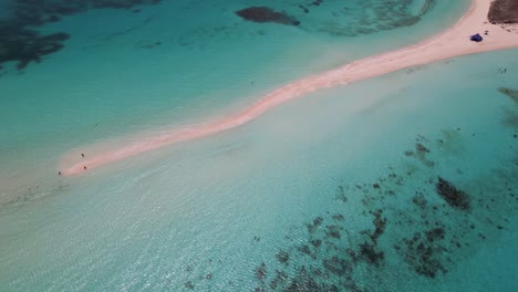 Aerial-top-view-coral-reef-tilt-up-reveal-tropical-sandbank-waves-crash-on-sand,-Los-Roques