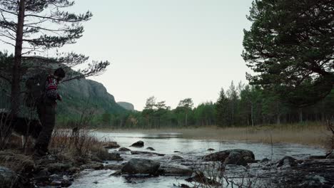 Hildremsvatnet,-Trondelag,-Norwegen-–-Ein-Mann,-Der-Mit-Seinem-Hund-über-Den-Felsigen-See-Läuft-–-Statische-Aufnahme
