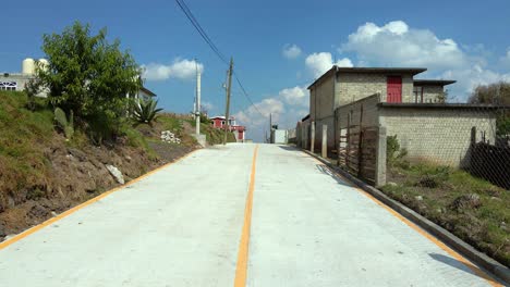 Dolly-in-a-new-and-lonely-road-with-low-budget-brick-houses,-delimitation-of-territory-with-steel-fences,-Almoloya,-State-of-Mexico
